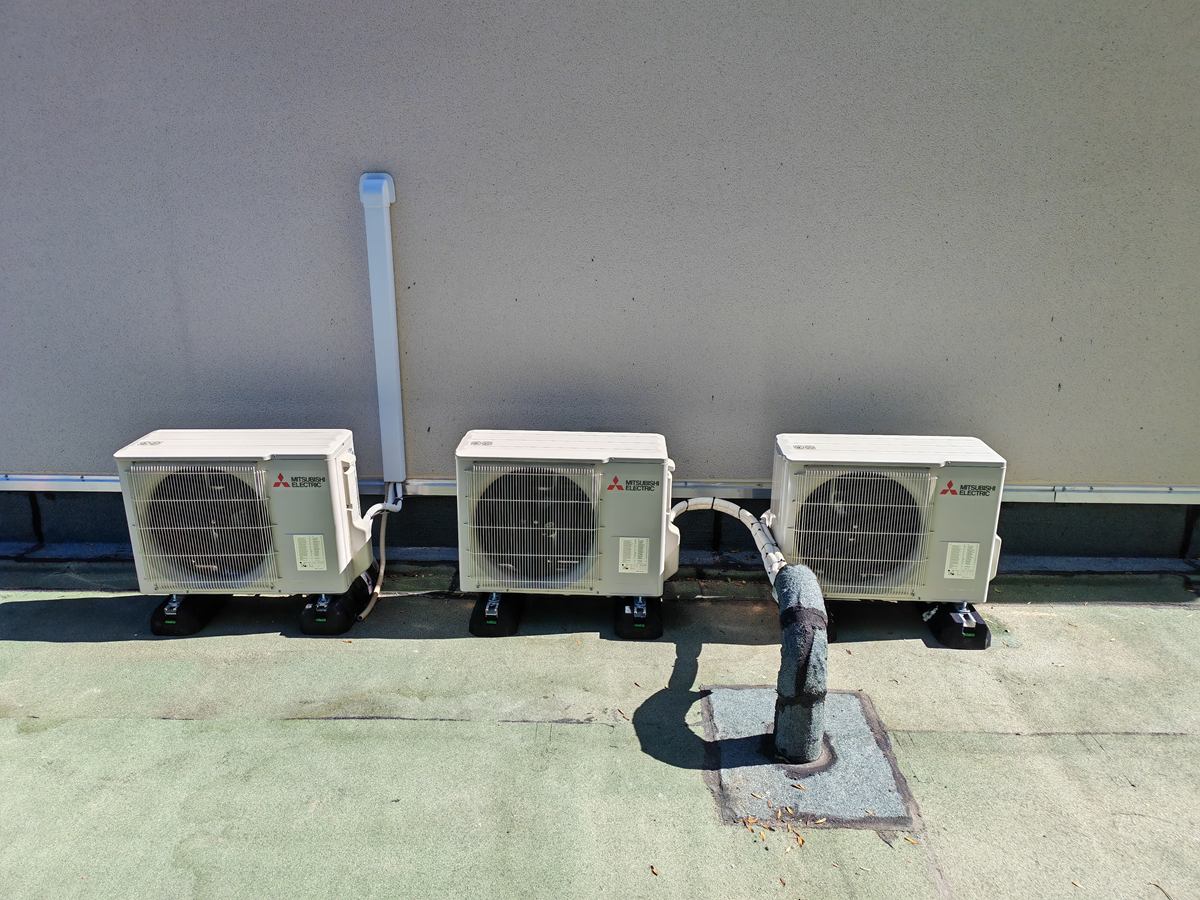 Trois groupes extérieurs de climatisation Mitsubishi Electric sur plots