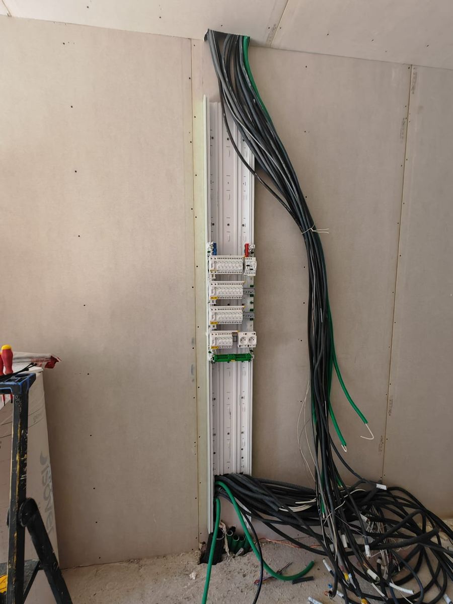 Gaine technique ouverte en cours de chantier, câbles électriques en attente jusqu’au sol
