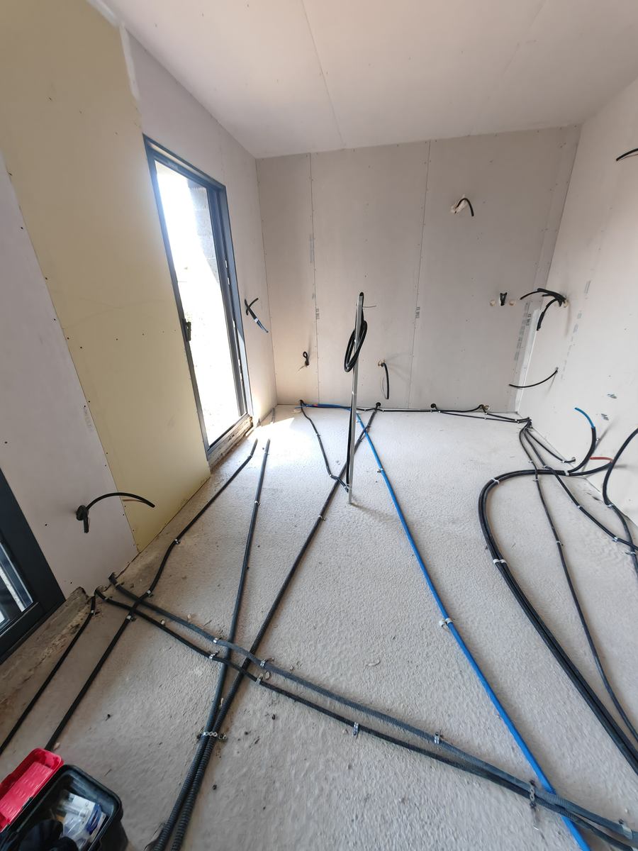 Gaines électriques et tubes de plomberie posés au sol dans une maison neuve